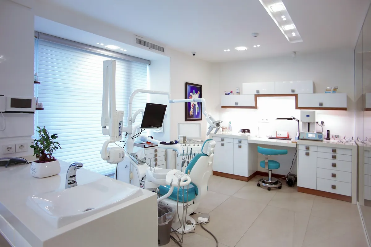 A bright, modern dental treatment room with a patient chair and equipment