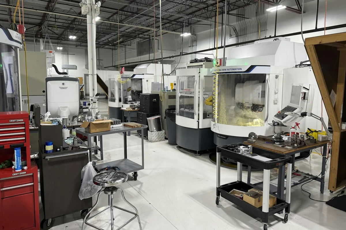 A row of CNC grinding machines on the floor of a precision machine shop
